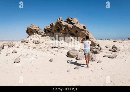 Donna prendendo stange rocks in immagine a Giardino di Roccia (Rock Zoo di Duqm o Duqm Stone Park), una famosa attrazione turistica di 3 kmq, Duqm, Oman Foto Stock