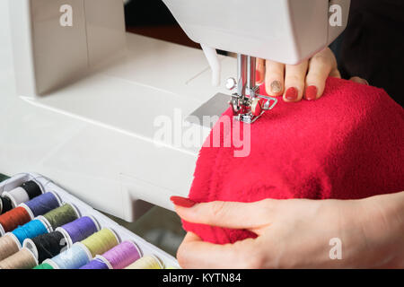 Giovane donna tessuto da cucire a macchina per cucire,processo di cucitura nella fase di overstitchin,steli colorati. Foto Stock