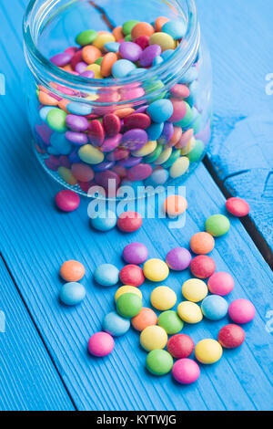 Colorato di cioccolatini in vaso sul tavolo blu. Foto Stock