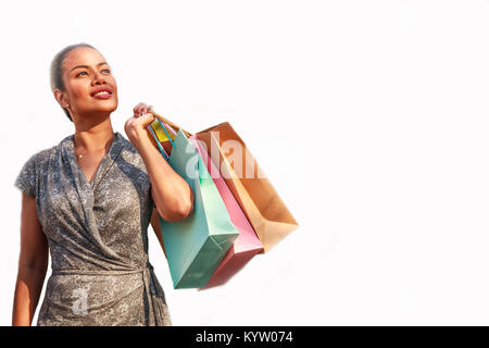 Donna asiatica shopper shopping e colorato di contenimento delle borse per lo shopping cercando sideway sulla sinistra e copiare lo spazio a destra, isolato su bianco backgrou Foto Stock