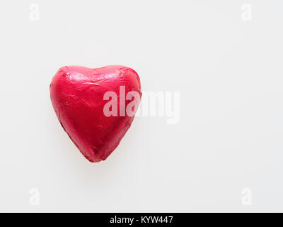 Forma di cuore cioccolato avvolto nel foglio in plastica rosso isolato su sfondo bianco utilizzare nel giorno di San Valentino o amore problema correlato Foto Stock