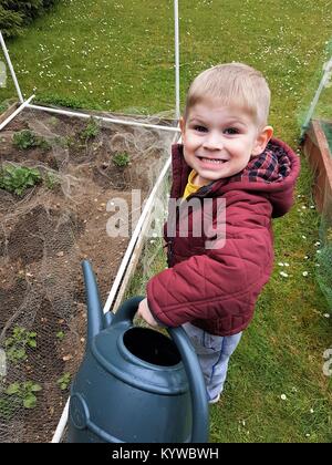 Ragazzo con big grin azienda acqua può Foto Stock