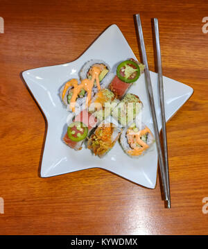 Un assortimento di sushi su una stella bianca con piastra in acciaio inox bacchette Foto Stock