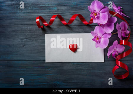 Orchidea viola e un involucro bianco su blu, sfondo di legno Foto Stock