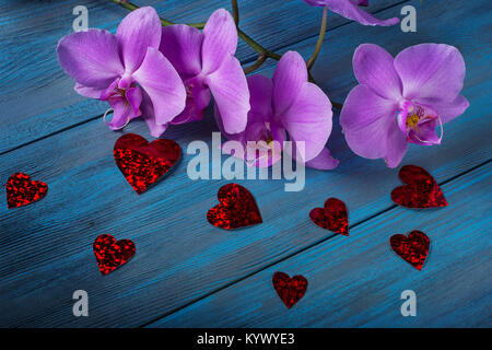 Orchidea viola e cuori sul blu, vecchio sfondo di legno Foto Stock