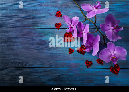 Orchidea viola e cuori sul blu, vecchio sfondo di legno Foto Stock