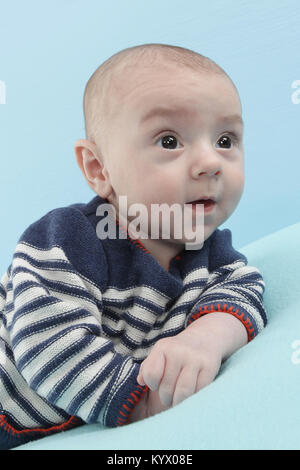 12 settimane vecchio baby boy esplorando il soffice coltre blu Foto Stock