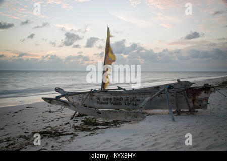 Dhow - barca di legno tradizionale giacente a secco al sorgere del sole su una spiaggia all'Oceano Indiano, isola di Zanzibar Foto Stock