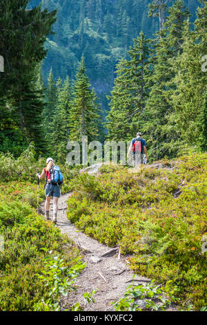 Un uomo e una donna escursioni sul lago spietato trail in stato di Washington Cascades. Foto Stock