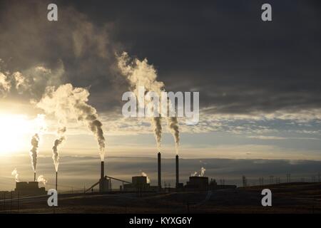 Le emissioni di carbonio che aumentano dalle pile di fumo di una centrale elettrica a carbone industriale al tramonto Foto Stock