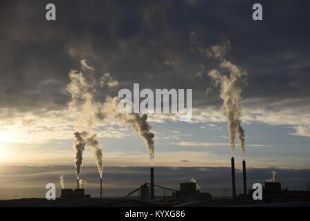 Le emissioni di carbonio che aumentano dalle pile di fumo di una centrale elettrica a carbone industriale al tramonto Foto Stock