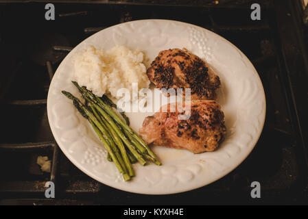 "Una cena piastra con riso, asparagi e pollo cotto in un forno seduto su una stufa. Foto Stock