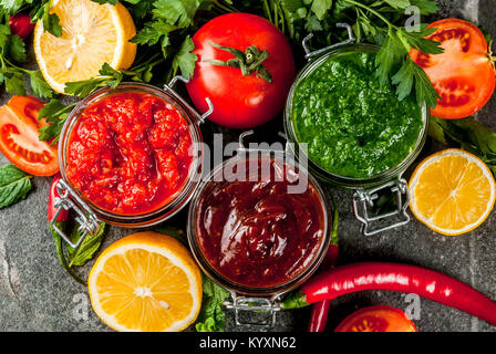 Indian cibo tradizionale, Set di tre chutney per Chaat e Sev Puri - dolce data-tamarindo, il coriandolo-verde menta e il peperoncino rosso aglio, sulla pietra scura b Foto Stock