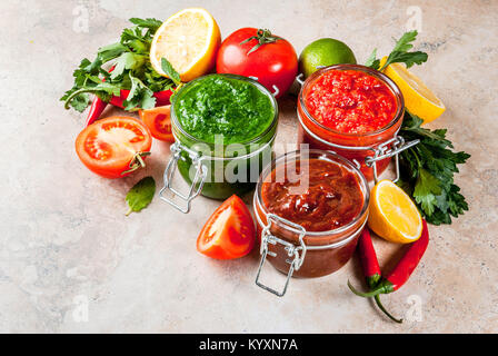 Indian cibo tradizionale, Set di tre chutney per Chaat e Sev Puri - dolce data-tamarindo, il coriandolo-verde menta e il peperoncino rosso aglio, sulla pietra beige Foto Stock