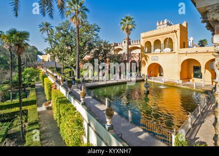 ALCAZAR siviglia spagna i giardini formali con i visitatori attorno MERCURYS PISCINA E FONTANA VISTO DA LA GALERIA DE GRUTESCOS passerella coperta Foto Stock