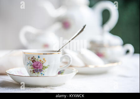 Porcellana di lusso set per il tè con una tazza, Teiera Zuccheriera sulla tovaglia bianca con bagel bianco su una piastra Foto Stock