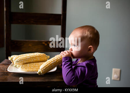 Vista laterale del simpatico baby girl mangiare materie calli a casa Foto Stock