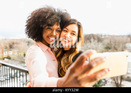 Allegro imprenditrici tenendo selfie con smart phone in hotel balcony Foto Stock