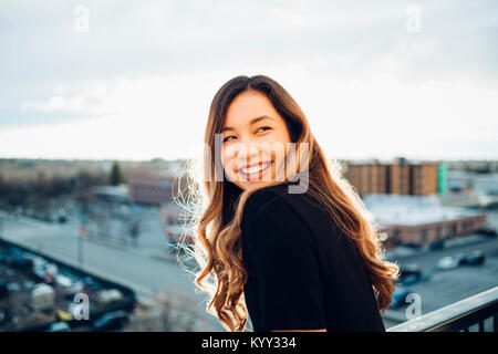 Allegro imprenditrice che guarda lontano mentre in piedi in hotel balcony Foto Stock