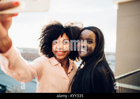 Sorridente imprenditrici tenendo selfie permanente, mentre in hotel balcony Foto Stock