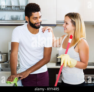 Felice giovani interracial matura la pulizia in cucina insieme e sorridente Foto Stock