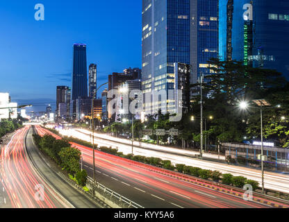 Incredibile vista notturna di traffico, catturate con una lunga esposizione, lungo la Gatot Subroto autostrada nel cuore di Jakarta business district al crepuscolo in Foto Stock