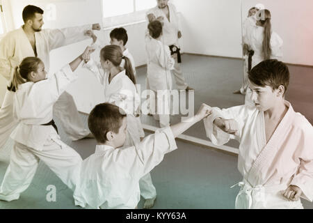Positivo diligente adolescenti praticanti di karate nuovo si muove in coppie in classe Foto Stock