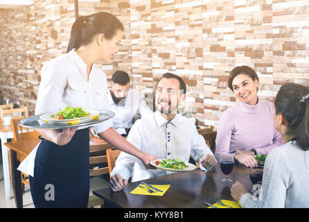 Donna sorridente cameriere portare per gli ospiti nel ristorante di campagna Foto Stock