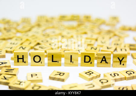 La parola holiday in piedi realizzato da legno lettere di scrabble su sfondo bianco Foto Stock