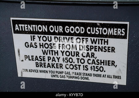 Un segnale di avvertimento in corrispondenza di un Chevron gas stazione self service pompa circa di guida off senza rimuovere la pistola dal serbatoio del gas. Foto Stock