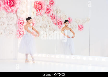 Giovane e incredibilmente bella ballerina è in posa e balli in un studio bianco pieno di luce. Foto Stock