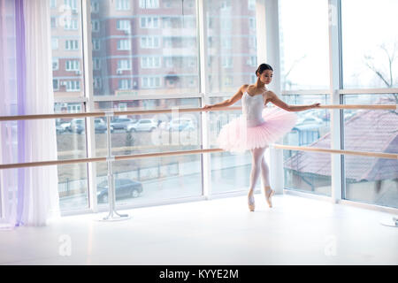 Giovane e incredibilmente bella ballerina è in posa e balli in un studio bianco pieno di luce. Foto Stock