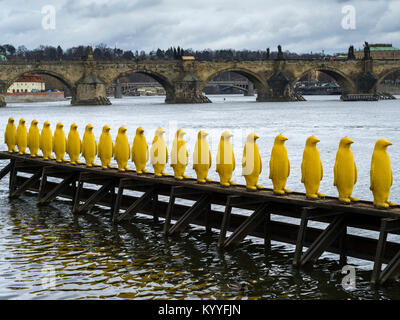 Fila di pinguini giallo sculture presso il Museo Kampa con Charles Bridge in background, Praga, Repubblica Ceca Foto Stock