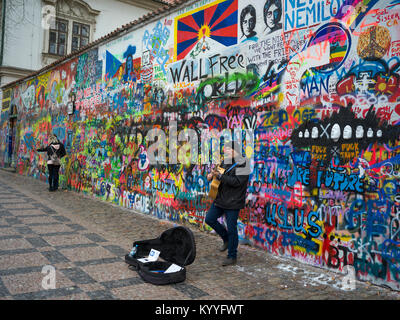 Street performer di fronte coperto di graffiti a parete, muro di John Lennon, Praga, Repubblica Ceca Foto Stock