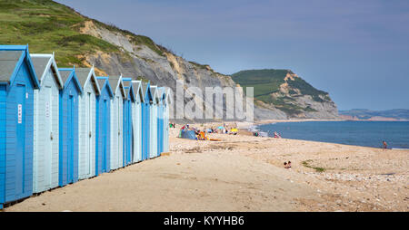 Blue beach capanne a Charmouth sulla spiaggia la costa del Dorset con Golden Cap in distanza Foto Stock