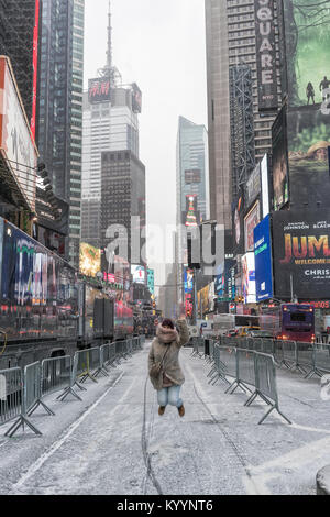 NYC/STATI UNITI D'America - 29 DEZ 2017 - giovane ragazza saltando in times square con la neve. Foto Stock