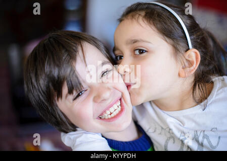 Bambini fratelli bacio sulla guancia di ridere e di giocare in casa Foto Stock