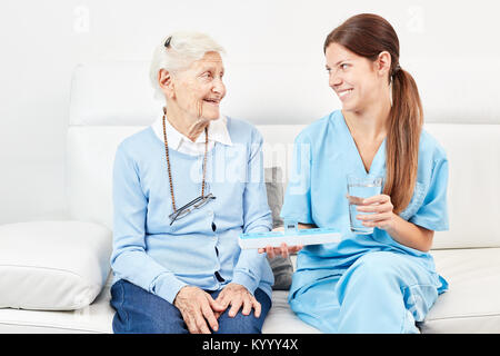 Femmina dà infermiere senior citizen un farmaco in casa di riposo o a casa Foto Stock