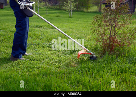 Uomo che taglia l'erba verde da tosaerba in giardino. Taglierina a benzina  Foto stock - Alamy