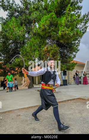 Villaggio Arsos, Cipro - 8 Ottobre 2017: uomo vestito in abiti tradizionali di eseguire il ballo folk, thrapani, holdng una falce, durante un festival. Foto Stock