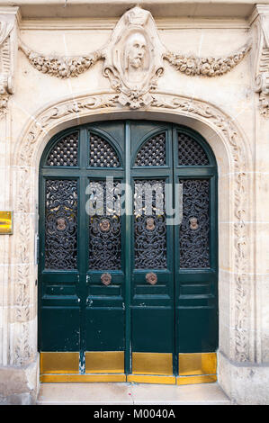 Un verde scuro porta ad arco con una decorazione a filigrana e oro kick piastre sono circondati da carving ornato nella facciata di pietra calcarea. Foto Stock