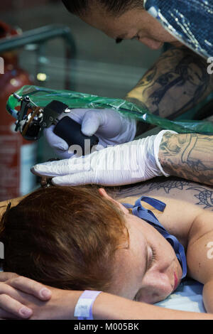 Tatuaggio artista al lavoro presso il Tattoo Convention di tabacco Dock, Londra, Inghilterra, Regno Unito Foto Stock