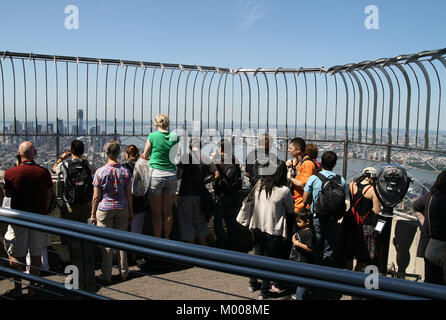 86º piano Observation Deck piena di turisti e di un gettone visualizzazione CANNOCCHIALE BINOCOLO sull'Empire State Building, nello Stato di New York, Stati Uniti d'America Foto Stock