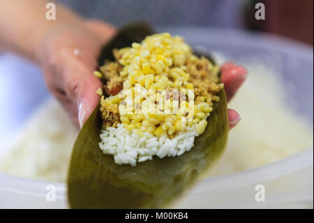 Vedendo i diversi strati di riempimento in un Hak Gar style jung/pacco di riso, riso, giallo piselli spezzati, dadi e più giallo piselli spezzati su una foglia di bambù Foto Stock