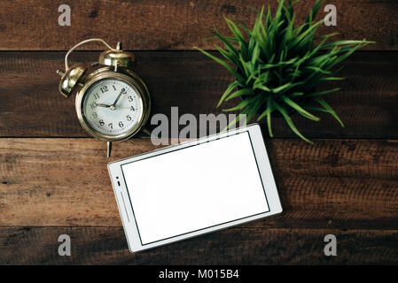 Orologio, pianta verde, tavoletta digitale su un tavolo di legno sfondo. business online e digitale il concetto di apprendimento Foto Stock