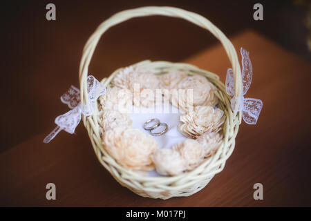 Gli anelli di nozze in un cesto decorato con nastri, il fuoco selettivo Foto Stock