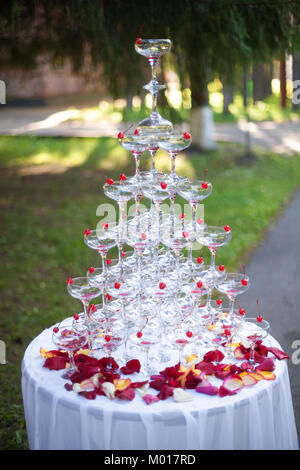 Piramide di vacanza wineglasses lucido con vino o champagne e petali di rosa Foto Stock