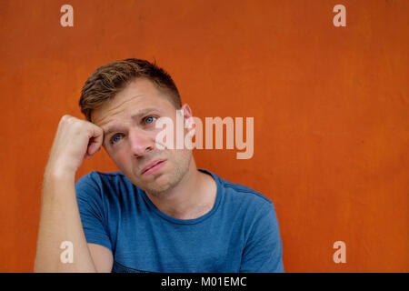 Close up ritratto di soggetti di razza caucasica deluso ha sottolineato giovane uomo su sfondo rosso. Egli è in procinto di piangere. Foto Stock