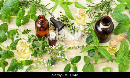 Erbe aromatiche fresche, fiori e oli essenziali sul pannello di legno Foto Stock