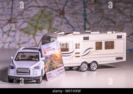 Modello caravan e auto con UK 'roulotte e camper Club' membership card e sfocati / mappa atlas. Concetto di touring utilizzando una rete di campeggio. Foto Stock